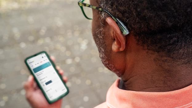 Man adjusting hearing aid settings on a phone